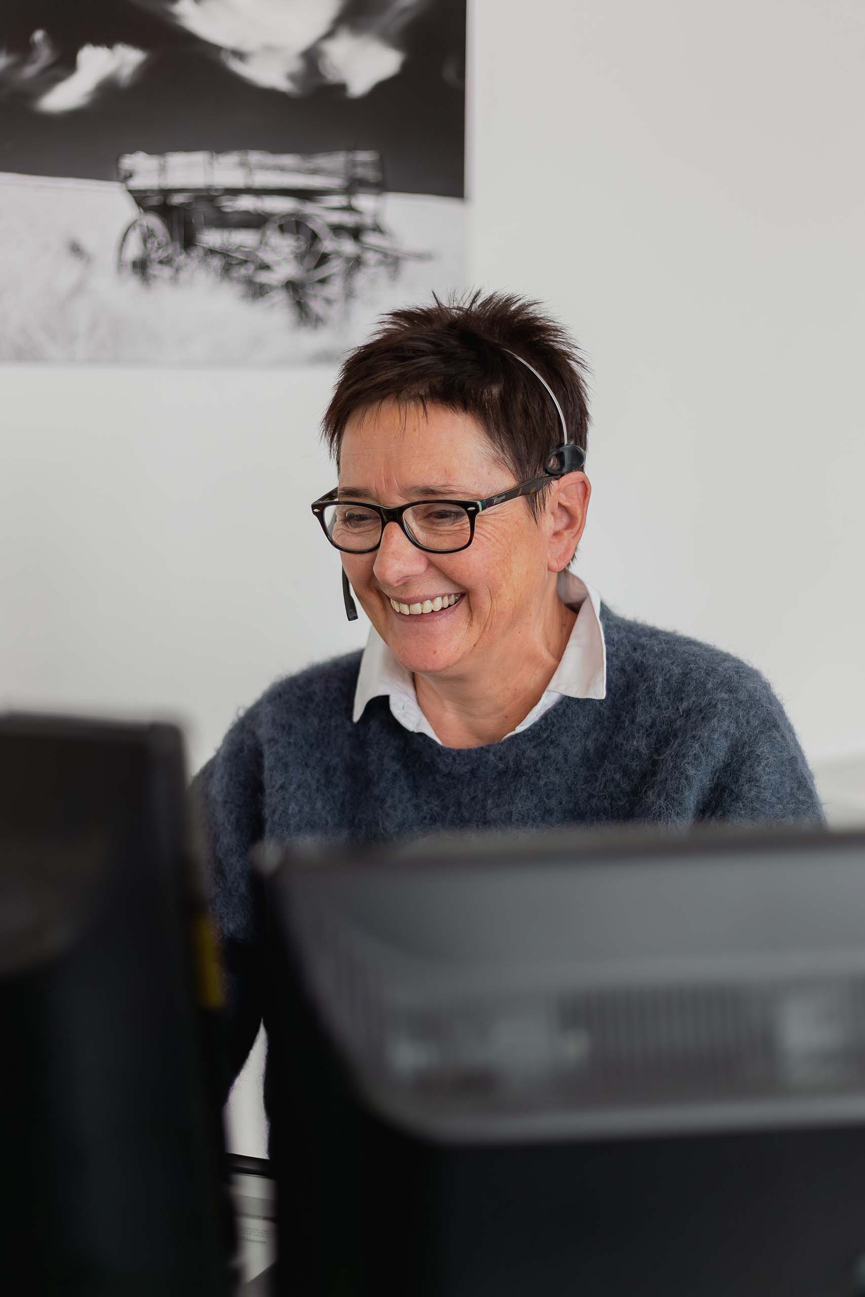 Engagiertes Beratungsgespräch in der Agentur: Mitarbeiterin lacht am Telefon mit Headset.