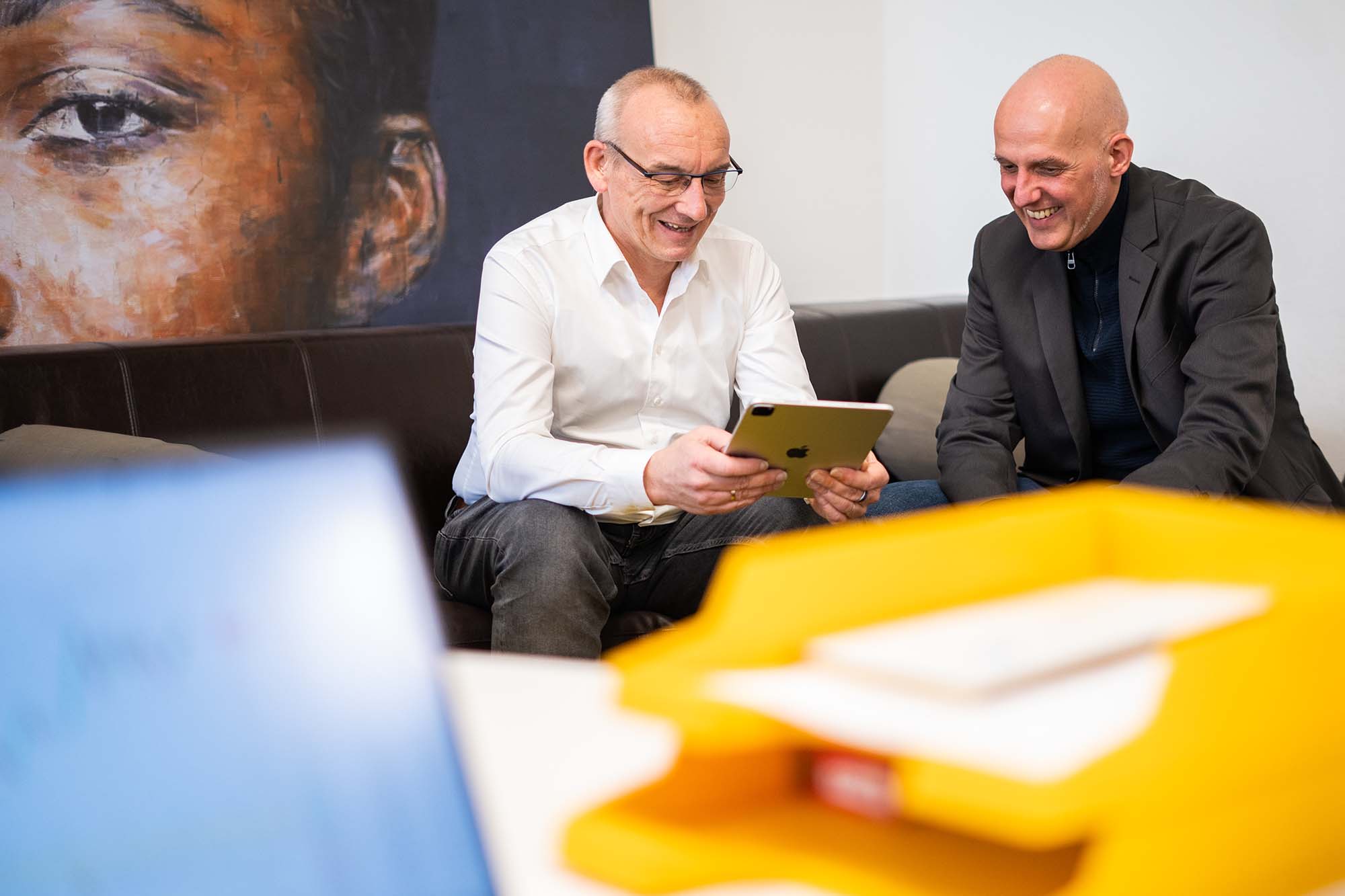 Geschäftsführer besprechen Digital Branding Strategien anhand einer Präsentation auf dem Tablet.