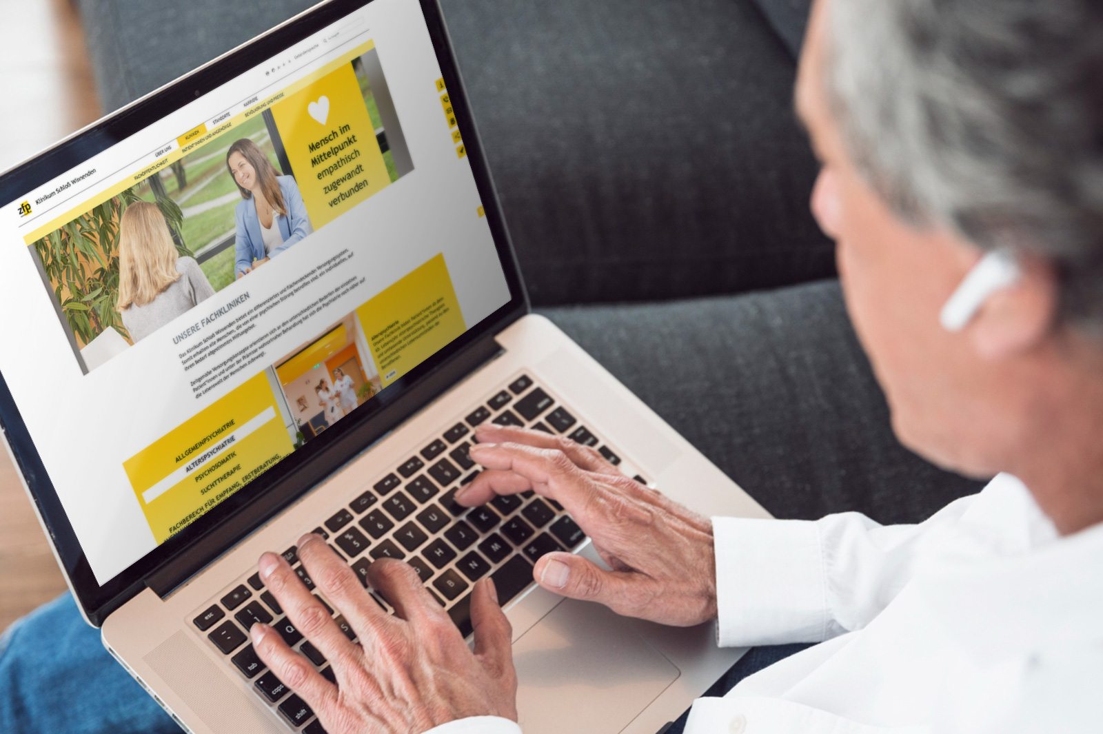 Person nutzt die Website des Klinikums Schloß Winnenden auf einem Laptop im Sitzen
