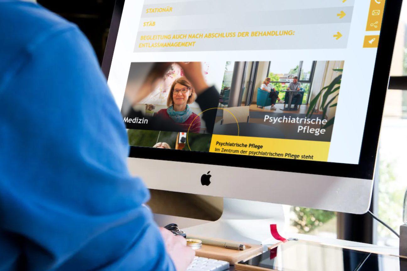 Person arbeitet an einem Desktop-Computer mit geöffneter Klinikseite zu Medizin und psychiatrischer Pflege
